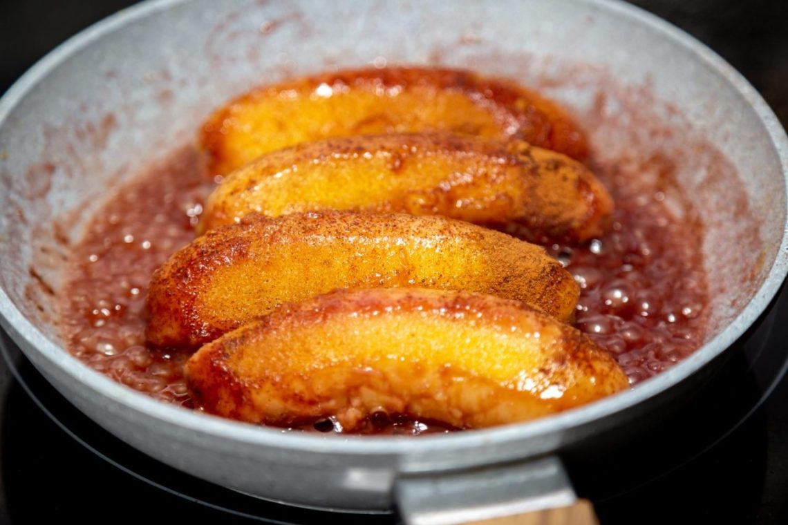Quartiers de pommes dorés et fondants, en train de caraméliser dans une poêle pour préparer une tarte Tatin.
