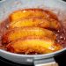Quartiers de pommes dorés et fondants, en train de caraméliser dans une poêle pour préparer une tarte Tatin.